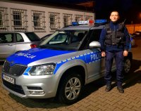 Policjant z Ogniwa Patrolowo-Interwencyjnego Komendy Powiatowej Policji w Hajnówce stoi przy radiowozie