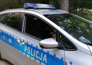Zdjęcie przedstawia radiowóz i policjanta siedzącego w środku.